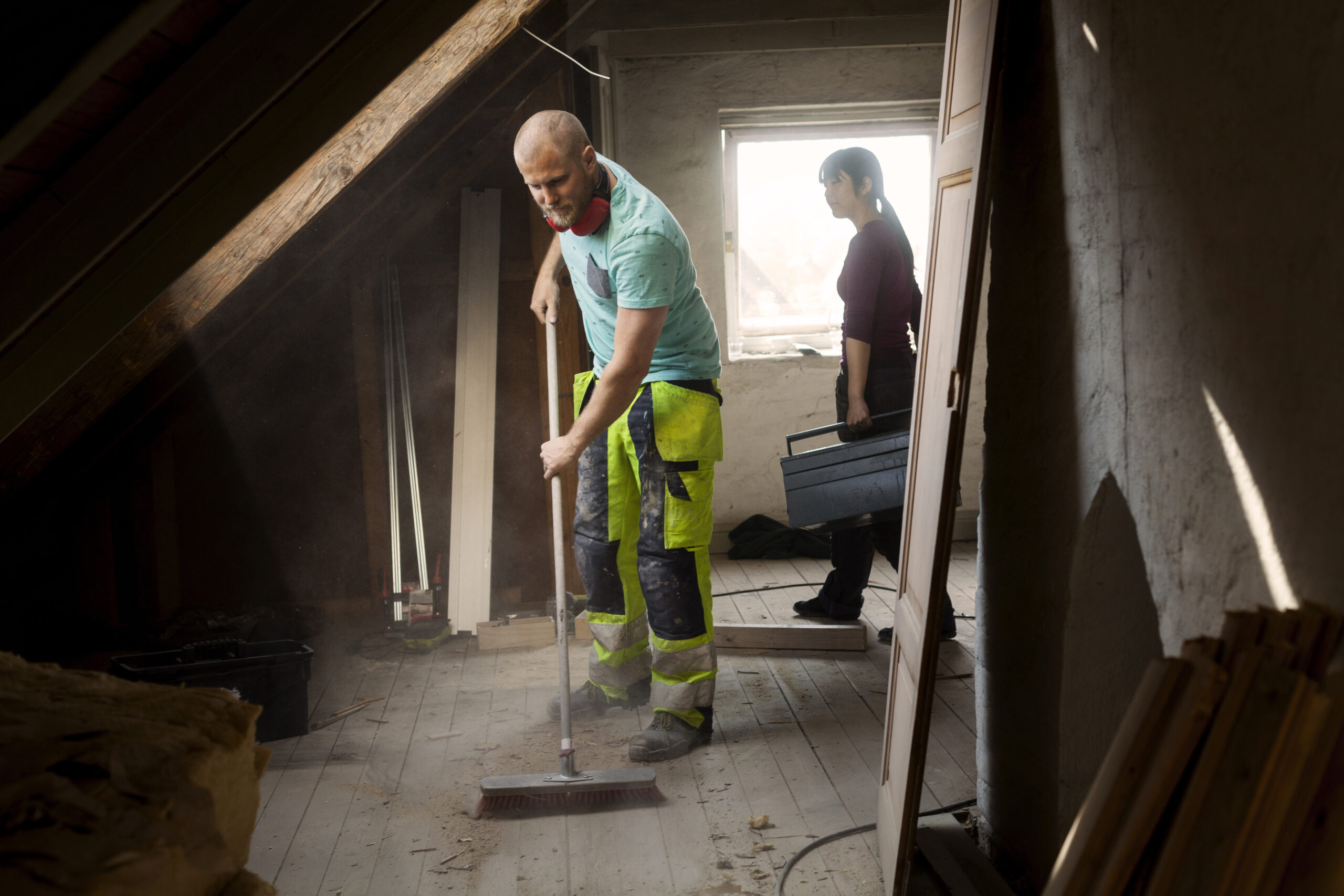 man sweeping floor in a sunlit attic renovation pr 2024 07 08 23 56 16 utc scaled