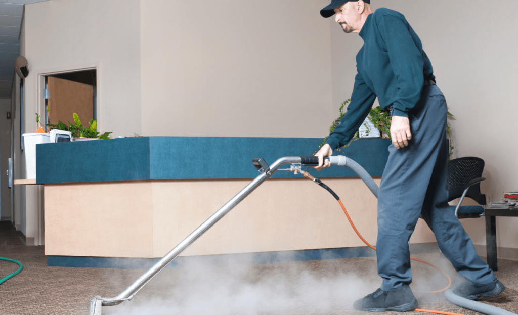 Cleaning professional using a steam cleaner to remove allergens from carpet fibers.